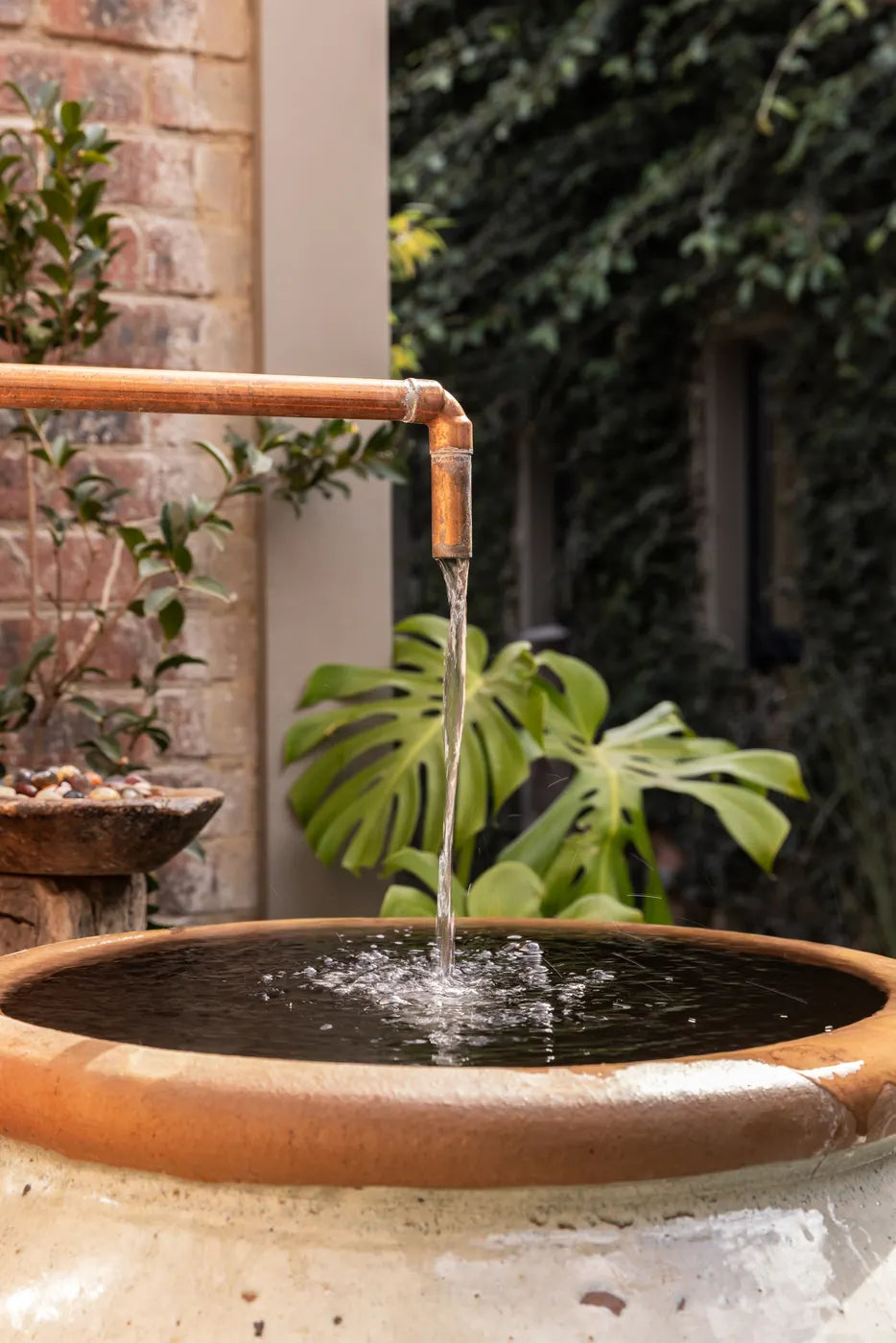 Copper water feature against a tiled wall at The Well